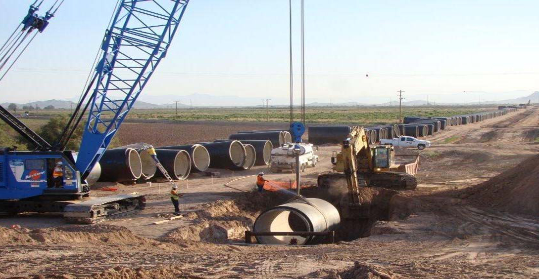 Crane lowering pipe into a hole